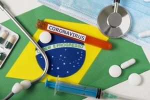 Coronavirus, nCoV concept. Top view protective breathing mask, stethoscope, syringe, pills on the flag of Brazil. photo