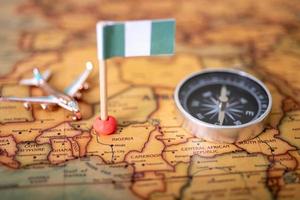 la bandera de nigeria, un avión y una brújula en el mapa mundial. foto