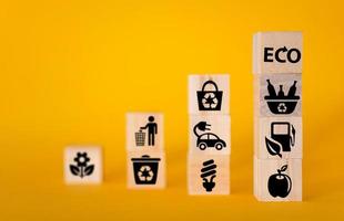 Ecology concept with icons on wooden cubes, yellow background. photo