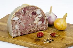 Chunk of meat product saltison. Pork homemade headcheese on wooden board. Delicious snack. Studio Photo