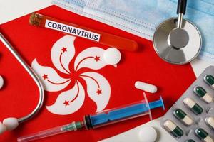 Coronavirus, nCoV concept. Top view protective breathing mask, stethoscope, syringe, pills on the Hong Kong flag . photo