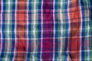 Folded crumpled multicolored checkered cotton fabric background texture. photo