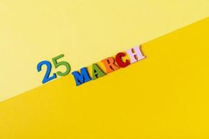 March 25, wooden letters on a yellow, paper background. photo