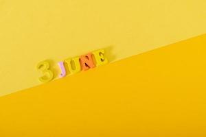 3 de junio. 3er día del mes, fecha natural. letras y números de madera sobre un fondo amarillo, día mundial de la bicicleta. foto