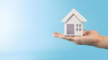 Hand holding house model in blue background for refinance plan and real estate concept. photo