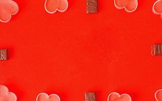 feliz día de san valentín muchos corazones románticos rosas y dulces de chocolate sobre fondo rojo. fondo romántico del día de san valentín foto