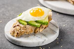 Healthy sandwich with fresh avocado and fried quail eggs photo