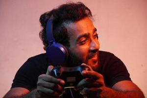 young man playing video game at home with Joystick and wearing headphone photo