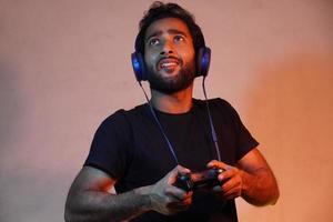 young man exited playing game at home with Joystick and wearing headphone photo