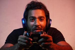 young man playing video game at home with Joystick and wearing headphone photo