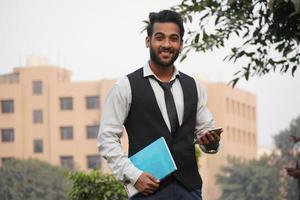 Image of happy Business wearing formal clothes smiling at camera with mobile in hands isolated over collage campus background photo