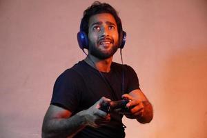 young man exited playing game at home with Joystick and wearing headphone photo