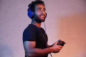 young man exited playing game at home with Joystick and wearing headphone photo