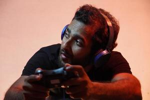 young man playing video game at home with Joystick and wearing headphone photo