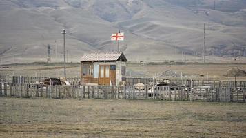 una cabaña de madera solitaria con una bandera nacional georgiana en una zona desierta. foto