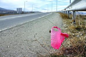 Pink polyethylene pash thrown away on the highway. photo