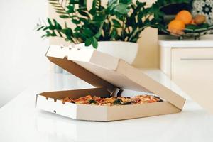 Pizza in a cardboard box on a white table background. Copy, empty space for text photo