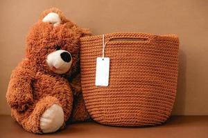 Toy teddy bear with a knitted bag on a brown background. Copy, empty space for text photo