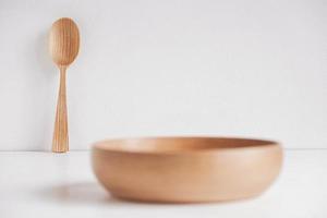 tazón de madera vacío y cuchara de madera sobre un fondo de mesa blanco. copiar, espacio vacío para texto foto