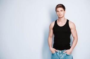Muscular model man in jeans and black t-shirt on a white background. Copy, empty space for text photo
