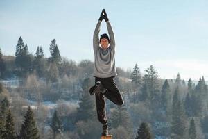 Caucasian senior man doing yoga exercises in front of amazing sunset on the winter mountains. Copy, empty space for text photo
