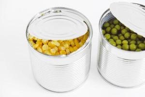 Two open cans with corn and peas on a white background. Copy, empty space for text photo
