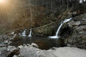 Small cascading waterfall among the rocks and forest. Beautiful mountain landscape. Copy, empty space for text photo
