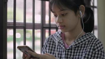 adorable adolescente disfruta chateando con amigos en el teléfono inteligente. video