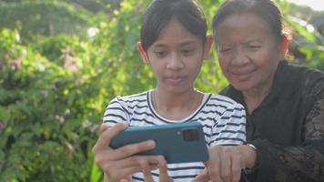 Teen girl and her elderly grandmother enjoy with video chat online from mobile smartphone.