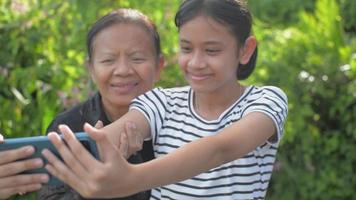 nipote allegra e sua nonna senior che scattano foto selfie con smartphone mobile. video