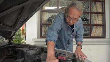 homem idoso verificando a condição das peças do motor de seu carro antigo. video