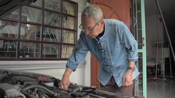 Senior man cleaning and checking engine parts of his old car after fixing at home. video