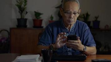 Senior man executive holding smartphone texting message in office at night. video