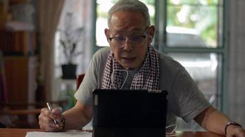 abuelo mayor viendo video tutorial para aprender lecciones en línea en tableta digital en casa.