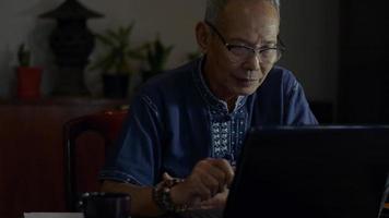 senior mannelijke executive die 's nachts naar een collega gaat met een videogesprek op het bureau. video