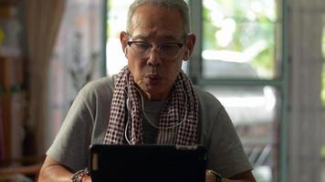 abuelo escribiendo en tableta digital mientras trabaja en el escritorio en casa. video