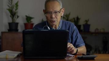 Senior businessman talking with coworker using webinar video call via laptop webcam on the desk.