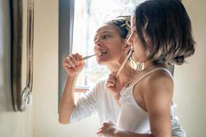 Mother and daughter at home brushing their teeth. photo