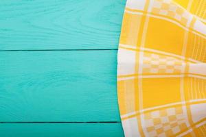 Yellow tablecloth on blue wooden table background. Top view and copy space. Mock up. photo