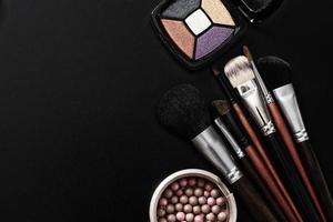 Cosmetic products on black background and make up tools. Top view and mock up. Copy space. photo