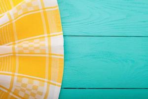 Yellow tablecloth on blue wooden table background. Top view and copy space. Mock up. photo