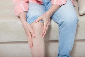 Cropped image of female sore knee. Woman at home background. Copy space and mock up. photo