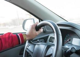 mano de hombre con un reloj en el volante de un coche moderno foto