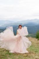 Beautiful bride posing in her wedding dress on a background of mountains. photo