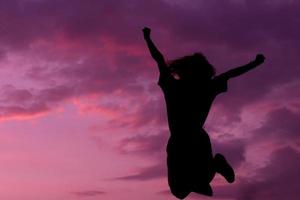 happy and strong confidence woman open arms and jump under the beautiful sunset photo