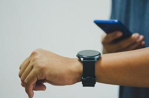 hombre de cerca con teléfono móvil conectado a un reloj inteligente. foto