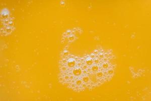 Bubbles on the surface of a yellow liquid as a background texture photo