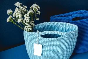 Two blue knitted handmade bag with flowers on a blue background. Copy, empty space for text photo