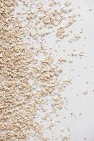 Dry oatmeal is randomly scattered on a white background. Top view. Copy, empty space for text photo