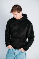 Portrait of a young man in black sweatshirt with hood on a white background. Copy, empty space for text photo